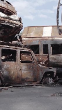 Bu stok dikey video Irpin, Bucha bölgesinde gri, düz, renksiz, yanmış arabaları gösteriyor.