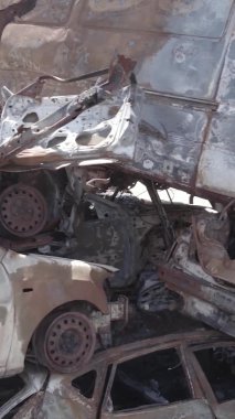 Bu stok dikey video Irpin, Bucha bölgesinde gri, düz, renksiz, yanmış arabaları gösteriyor.
