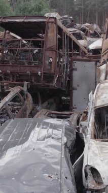 Bu stok dikey video Irpin, Bucha bölgesinde gri, düz, renksiz, yanmış arabaları gösteriyor.