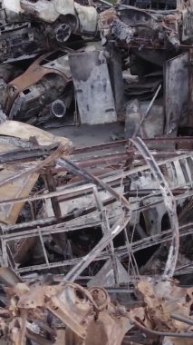 Bu stok dikey video Irpin, Bucha bölgesinde gri, düz, renksiz, yanmış arabaları gösteriyor.