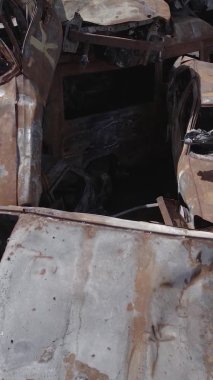 Bu stok dikey video Irpin, Bucha bölgesinde gri, düz, renksiz, yanmış arabaları gösteriyor.