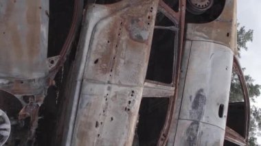 Bu stok dikey video Irpin, Bucha bölgesinde gri, düz, renksiz, yanmış arabaları gösteriyor.