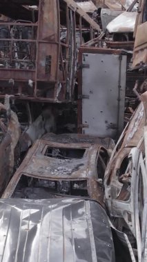Bu stok dikey video Irpin, Bucha bölgesinde gri, düz, renksiz, yanmış arabaları gösteriyor.
