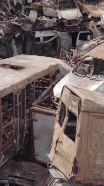 Bu stok dikey video Irpin, Bucha bölgesinde gri, düz, renksiz, yanmış arabaları gösteriyor.