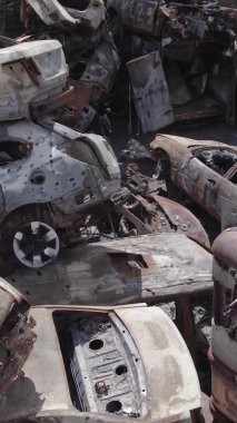 Bu stok dikey video Irpin, Bucha bölgesinde gri, düz, renksiz, yanmış arabaları gösteriyor.