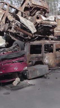 Bu stok dikey video Irpin, Bucha bölgesinde gri, düz, renksiz, yanmış arabaları gösteriyor.