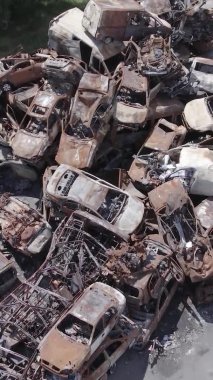 Bu stok dikey video Irpin, Bucha bölgesinde gri, düz, renksiz, yanmış arabaları gösteriyor.