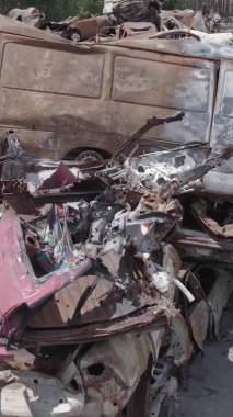 Bu stok dikey video Irpin, Bucha bölgesinde gri, düz, renksiz, yanmış arabaları gösteriyor.