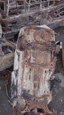 Bu stok dikey video Irpin, Bucha bölgesinde gri, düz, renksiz, yanmış arabaları gösteriyor.