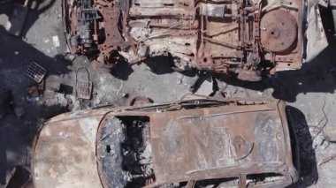 Bu stok dikey video Irpin, Bucha bölgesinde gri, düz, renksiz, yanmış arabaları gösteriyor.