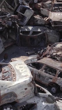 Bu stok dikey video Irpin, Bucha bölgesinde gri, düz, renksiz, yanmış arabaları gösteriyor.