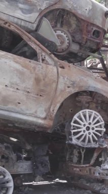 Bu stok dikey video Irpin, Bucha bölgesinde gri, düz, renksiz, yanmış arabaları gösteriyor.