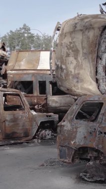 Bu stok dikey video Irpin, Bucha bölgesinde gri, düz, renksiz, yanmış arabaları gösteriyor.