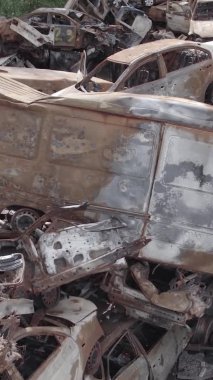 Bu stok dikey video Irpin, Bucha bölgesinde gri, düz, renksiz, yanmış arabaları gösteriyor.