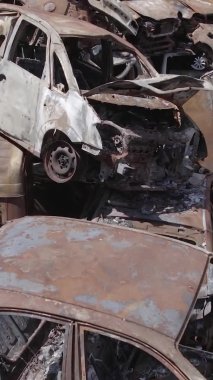 Bu stok dikey video Irpin, Bucha bölgesinde gri, düz, renksiz, yanmış arabaları gösteriyor.