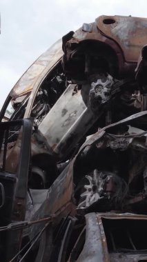 Bu stok dikey video Irpin, Bucha bölgesinde gri, düz, renksiz, yanmış arabaları gösteriyor.