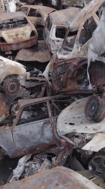 Bu stok dikey video Irpin, Bucha bölgesinde gri, düz, renksiz, yanmış arabaları gösteriyor.