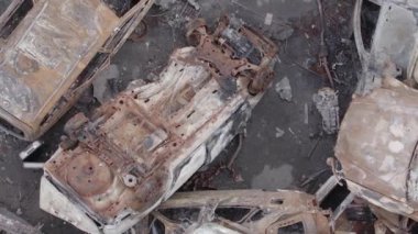 Bu stok dikey video Irpin, Bucha bölgesinde gri, düz, renksiz, yanmış arabaları gösteriyor.