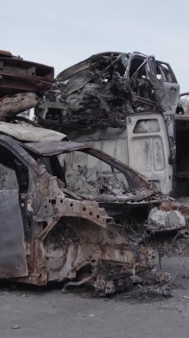 Bu stok dikey video Irpin, Bucha bölgesinde gri, düz, renksiz, yanmış arabaları gösteriyor.
