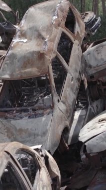 Bu stok dikey video Irpin, Bucha bölgesinde gri, düz, renksiz, yanmış arabaları gösteriyor.