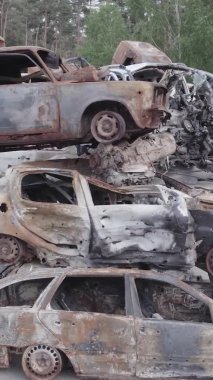 Bu stok dikey video Irpin, Bucha bölgesinde gri, düz, renksiz, yanmış arabaları gösteriyor.