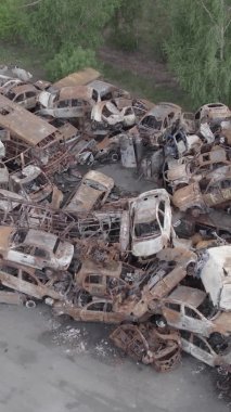 Bu stok dikey video Irpin, Bucha bölgesinde gri, düz, renksiz, yanmış arabaları gösteriyor.