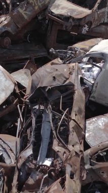 Bu stok dikey video Irpin, Bucha bölgesinde gri, düz, renksiz, yanmış arabaları gösteriyor.