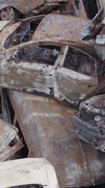 Bu stok dikey video Irpin, Bucha bölgesinde gri, düz, renksiz, yanmış arabaları gösteriyor.