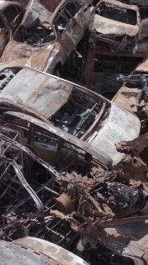 Bu stok dikey video Irpin, Bucha bölgesinde gri, düz, renksiz, yanmış arabaları gösteriyor.