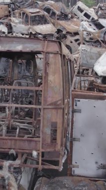 Bu stok dikey video Irpin, Bucha bölgesinde gri, düz, renksiz, yanmış arabaları gösteriyor.