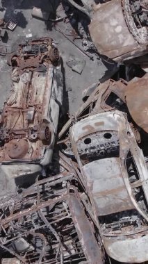 Bu stok dikey video Irpin, Bucha bölgesinde gri, düz, renksiz, yanmış arabaları gösteriyor.