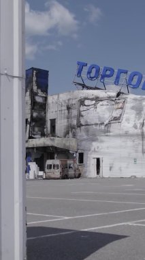 Bu dikey video, Bucha, Ukrayna 'da bir alışveriş merkezinin savaş tarafından tahrip edildiğini gösteriyor. Ağır çekim, gri, renksiz, düz.