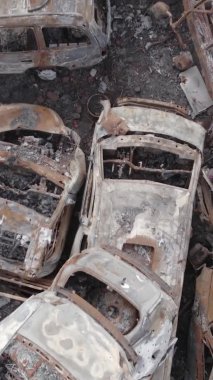 Bu stok dikey video Irpin, Bucha bölgesinde gri, düz, renksiz, yanmış arabaları gösteriyor.