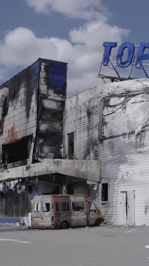 Bu dikey video, Bucha, Ukrayna 'da bir alışveriş merkezinin savaş tarafından tahrip edildiğini gösteriyor. Ağır çekim, gri, renksiz, düz.