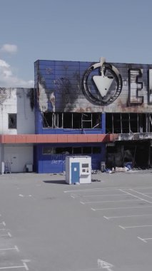 Bu dikey video, Bucha, Ukrayna 'da bir alışveriş merkezinin savaş tarafından tahrip edildiğini gösteriyor. Ağır çekim, gri, renksiz, düz.