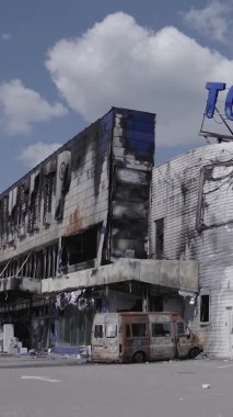 Bu dikey video, Bucha, Ukrayna 'da bir alışveriş merkezinin savaş tarafından tahrip edildiğini gösteriyor. Ağır çekim, gri, renksiz, düz.