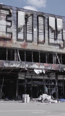 Bu dikey video, Bucha, Ukrayna 'da bir alışveriş merkezinin savaş tarafından tahrip edildiğini gösteriyor. Ağır çekim, gri, renksiz, düz.