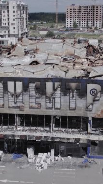 Bu dikey video, Bucha, Ukrayna 'da bir alışveriş merkezinin savaş tarafından tahrip edildiğini gösteriyor. Ağır çekim, gri, renksiz, düz.