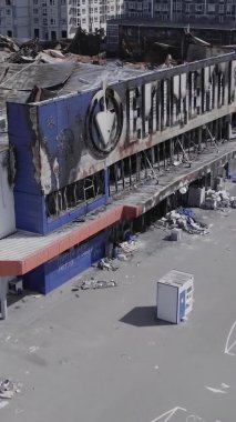 Bu dikey video, Bucha, Ukrayna 'da bir alışveriş merkezinin savaş tarafından tahrip edildiğini gösteriyor. Ağır çekim, gri, renksiz, düz.