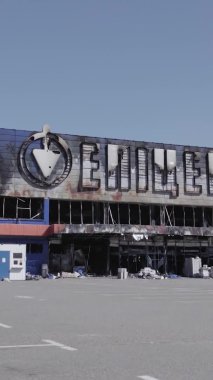 Bu dikey video, Bucha, Ukrayna 'da bir alışveriş merkezinin savaş tarafından tahrip edildiğini gösteriyor. Ağır çekim, gri, renksiz, düz.