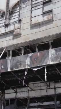 Bu dikey video, Bucha, Ukrayna 'da bir alışveriş merkezinin savaş tarafından tahrip edildiğini gösteriyor. Ağır çekim, gri, renksiz, düz.