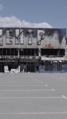 Bu dikey video, Bucha, Ukrayna 'da bir alışveriş merkezinin savaş tarafından tahrip edildiğini gösteriyor. Ağır çekim, gri, renksiz, düz.