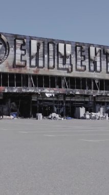 Bu dikey video, Bucha, Ukrayna 'da bir alışveriş merkezinin savaş tarafından tahrip edildiğini gösteriyor. Ağır çekim, gri, renksiz, düz.