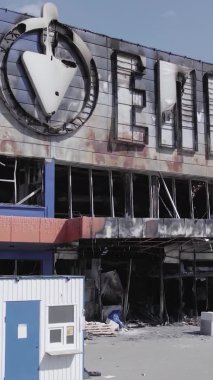 Bu dikey video, Bucha, Ukrayna 'da bir alışveriş merkezinin savaş tarafından tahrip edildiğini gösteriyor. Ağır çekim, gri, renksiz, düz.