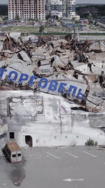 Bu dikey video, Bucha, Ukrayna 'da bir alışveriş merkezinin savaş tarafından tahrip edildiğini gösteriyor. Ağır çekim, gri, renksiz, düz.