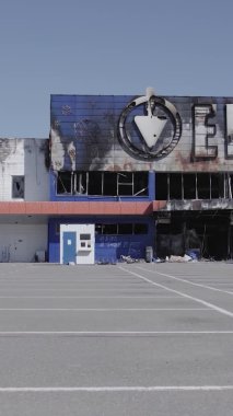 Bu dikey video, Bucha, Ukrayna 'da bir alışveriş merkezinin savaş tarafından tahrip edildiğini gösteriyor. Ağır çekim, gri, renksiz, düz.