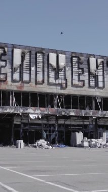 Bu dikey video, Bucha, Ukrayna 'da bir alışveriş merkezinin savaş tarafından tahrip edildiğini gösteriyor. Ağır çekim, gri, renksiz, düz.