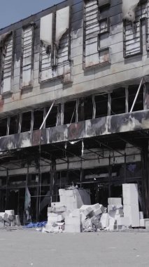 Bu dikey video, Bucha, Ukrayna 'da bir alışveriş merkezinin savaş tarafından tahrip edildiğini gösteriyor. Ağır çekim, gri, renksiz, düz.