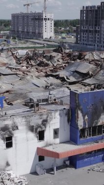 Bu dikey video, Bucha, Ukrayna 'da bir alışveriş merkezinin savaş tarafından tahrip edildiğini gösteriyor. Ağır çekim, gri, renksiz, düz.