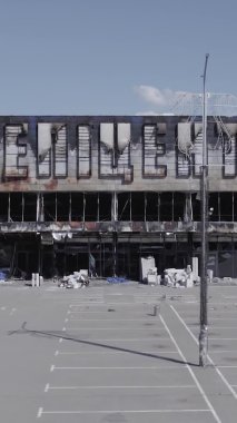 Bu dikey video, Bucha, Ukrayna 'da bir alışveriş merkezinin savaş tarafından tahrip edildiğini gösteriyor. Ağır çekim, gri, renksiz, düz.